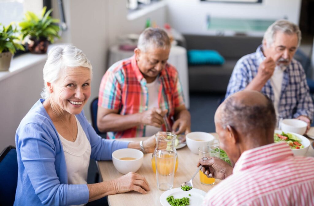 a group of seniors sit at a table eating peas and chatting