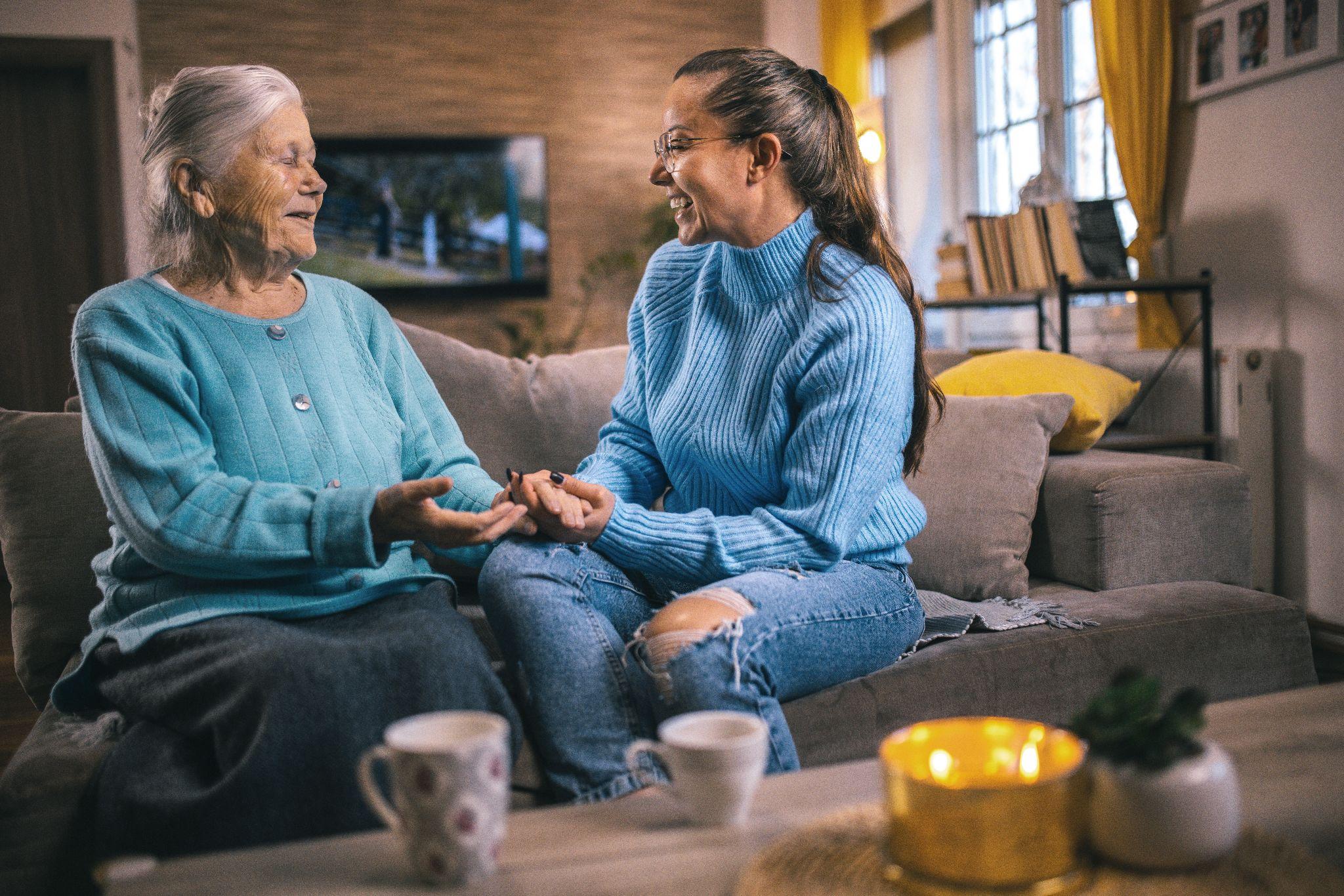 An elderly woman and an older adult talking to each other over a cup of tea.